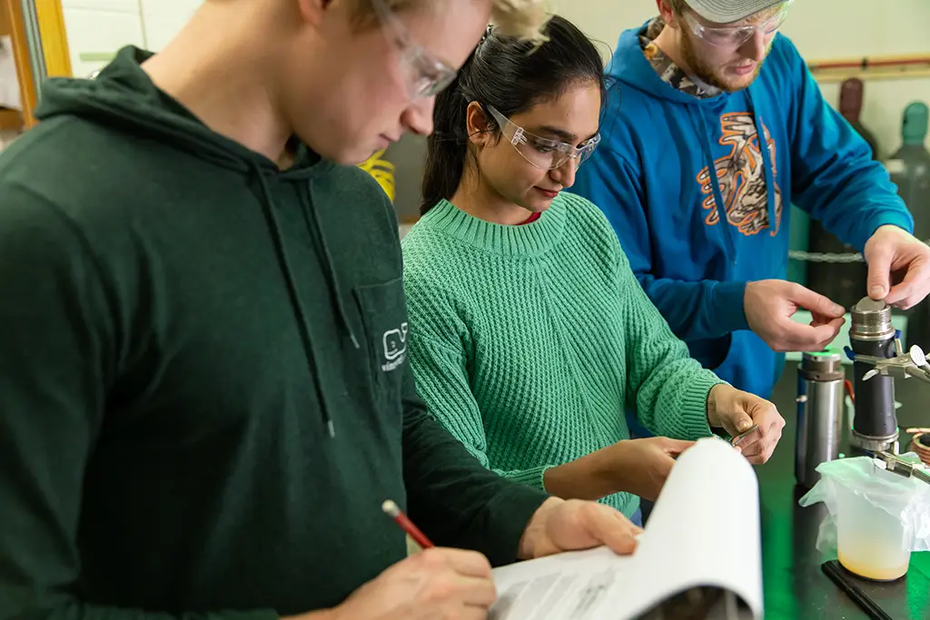 Geological engineering students conducting field research and taking notes on a technical project inside a college laboratory.