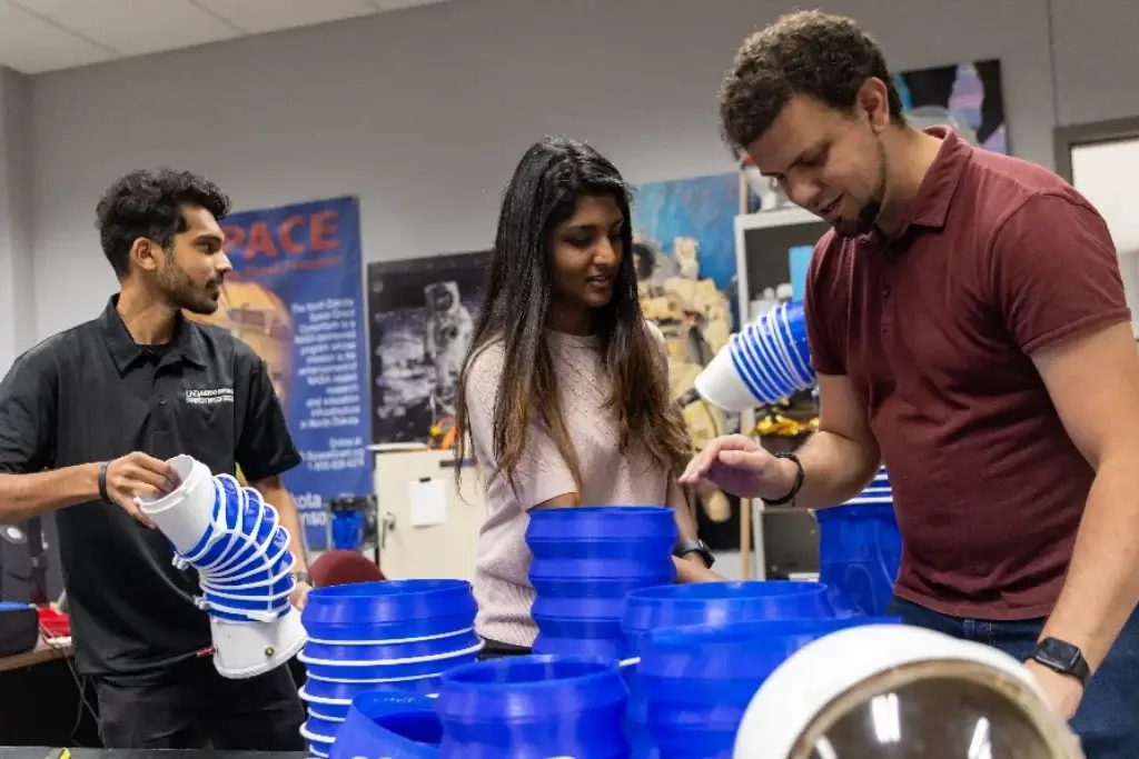 Three aerospace engineering students are working on a new project, meticulously designing and testing their innovative concepts