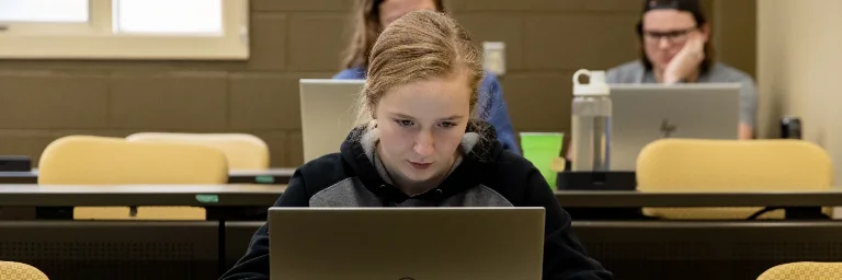A female criminal justice student is deeply focused on her laptop