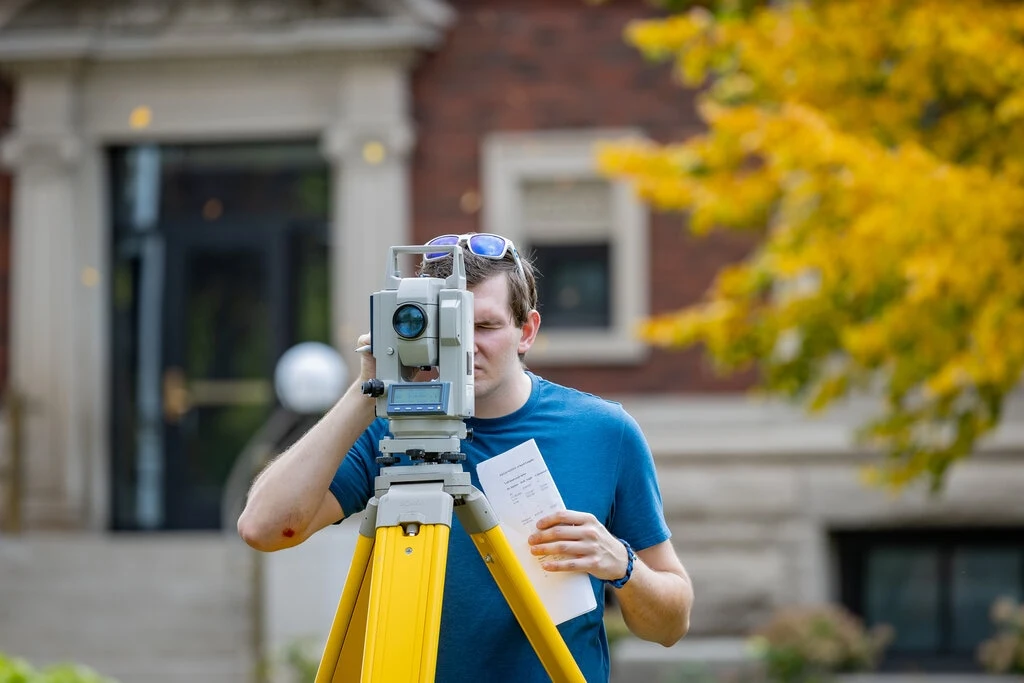 A civil engineering student is utilizing a laser tripod machine for a project.