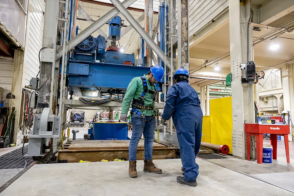 Two petroleum engineering students training on the large scale drilling rig simulator in the university's research lab.