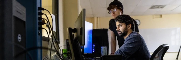 Two software engineers in their office, deeply focused on their computer screens as they work together