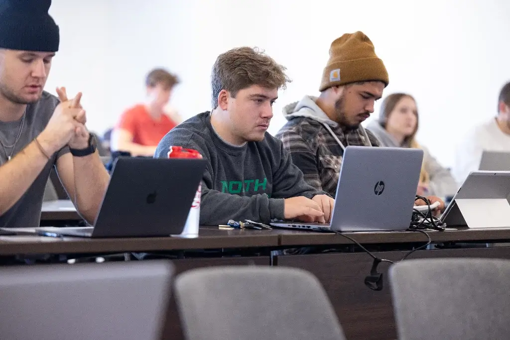 Business students in a classroom using laptops