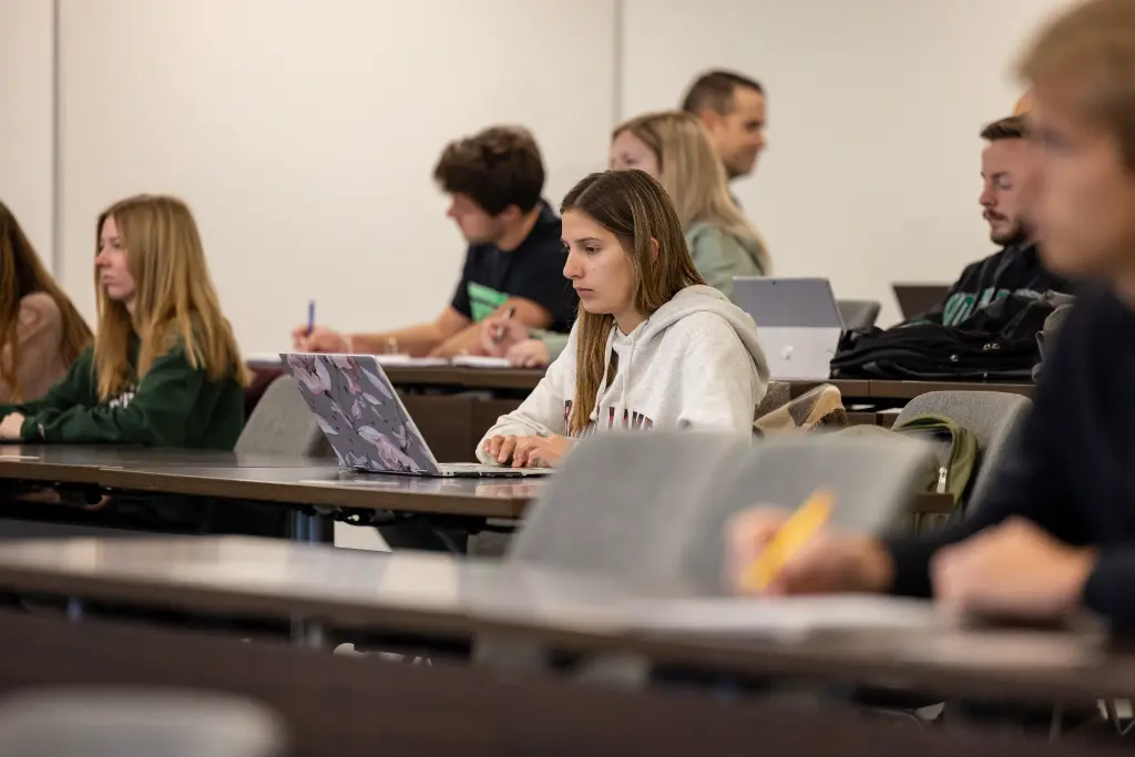 A lively applied economics class where students are actively using laptops to enhance their learning experience.