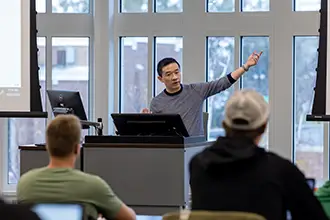 A professor delivering a lecture to a class of applied economics students.