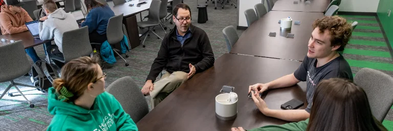 A political science professor and some students are having a discussion in a classroom.