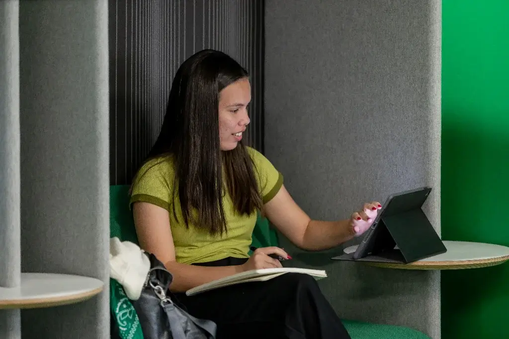 A business management student with her tablet, writing and studying in a study cubicle