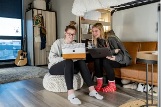 Two female students study side by side in their room