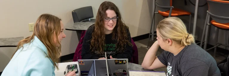 Three female data science students gathered together to study for their upcoming exam.