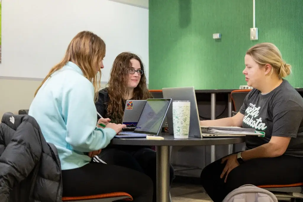 Three female data science students are sitting in the campus library, preparing for their project presentation