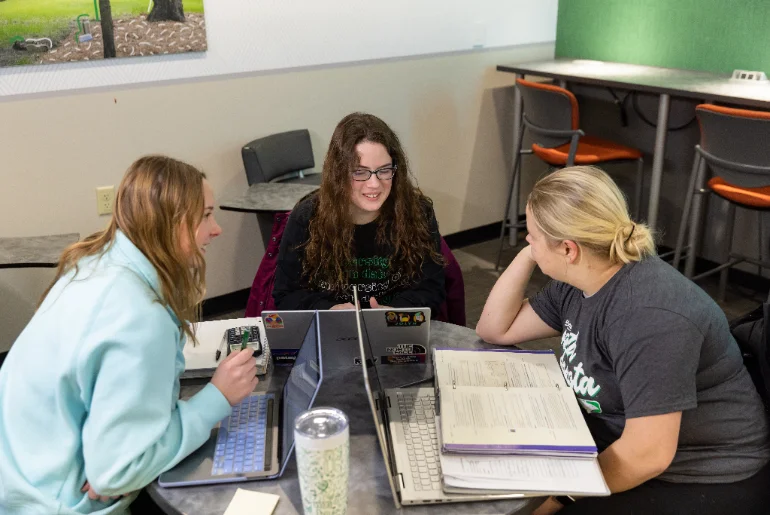 three UND cyber security students with laptops