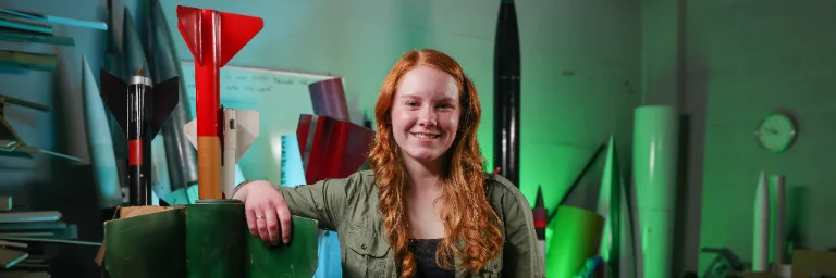 female student next to rocket models