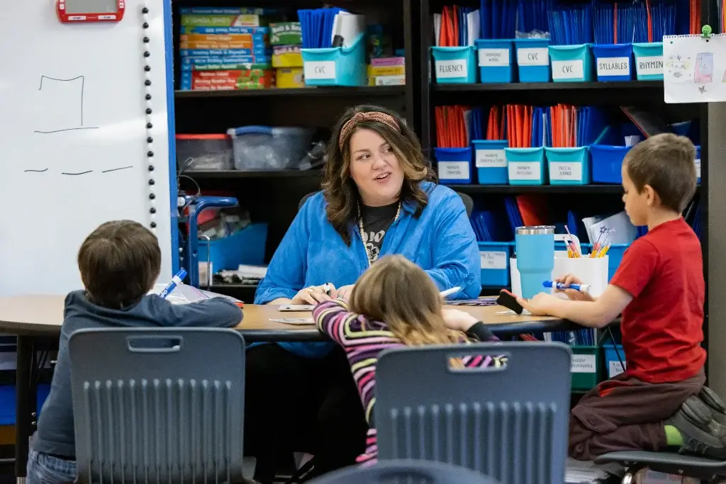  a special education teacher seated with her students around the same table