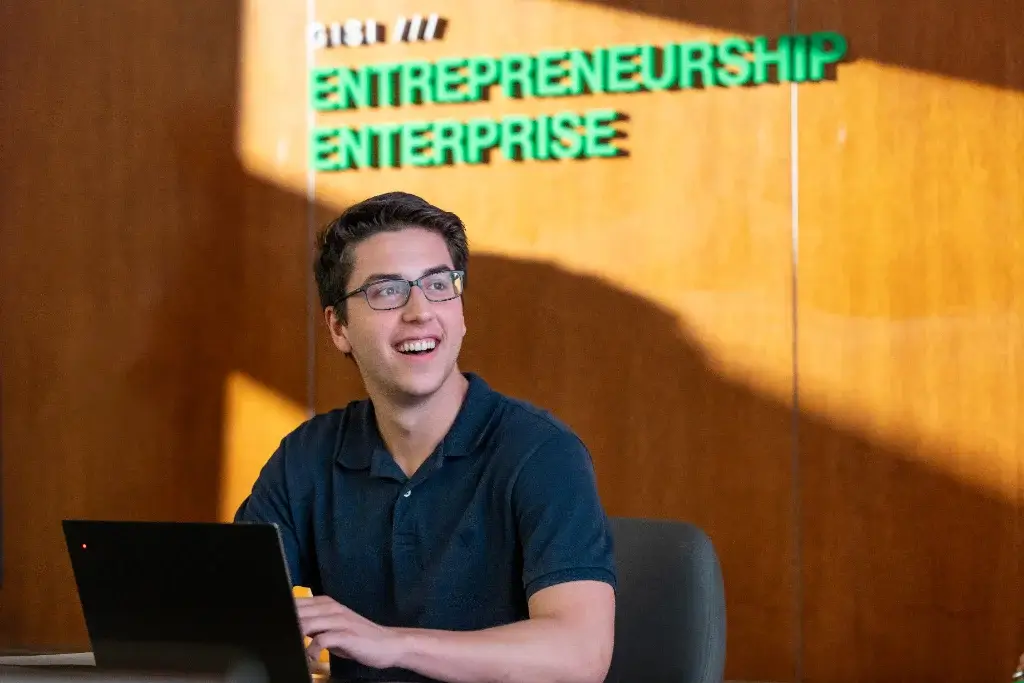 A business management student in a meeting room, laughing while discussing a project with colleagues