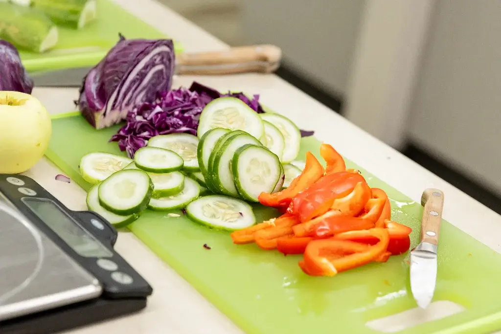 Chopped vegetables including cucumbers, red bell peppers, and cabbage, promoting healthy nutrition