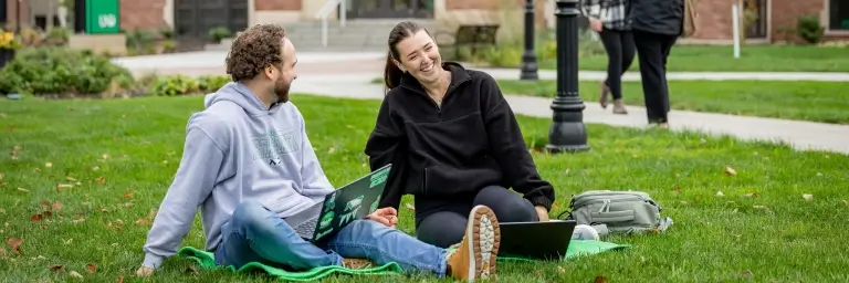 Students sitting in the grass on campus