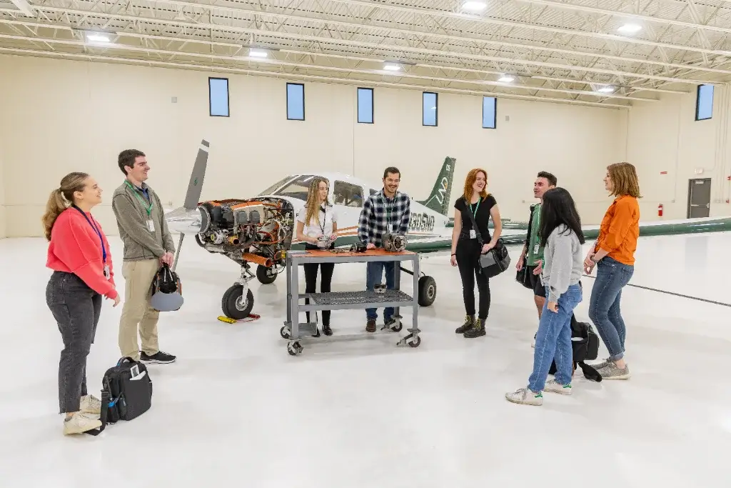 a group of students next to a plane in a hangar