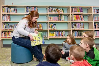 A UND early childhood student reading to young children.