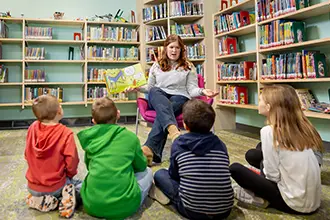 A UND early childhood student reading to young children.