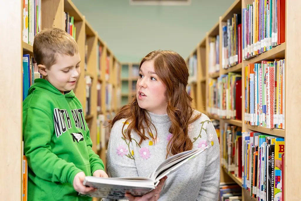 A UND student engaging with a child while explaining a book