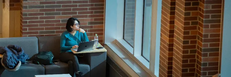 A space science student researching on a laptop in a lobby