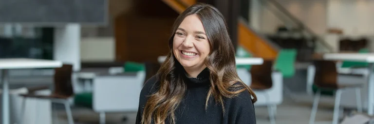 A business management student smiling while sitting in the campus cafeteria