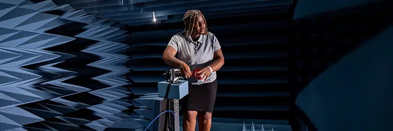 An engineering student working with specialized equipment in a soundproof testing lab, representing the hands-on and technical nature of engineering careers.