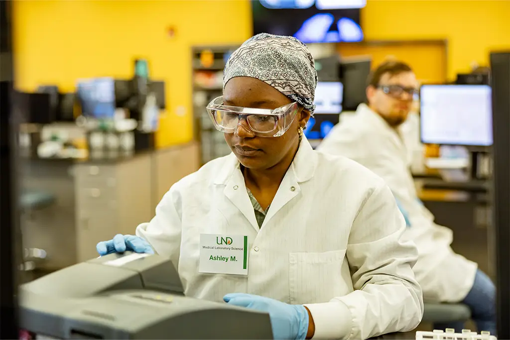 Laboratory professional inputting data and loading samples into a high-tech medical analyzer for rapid testing