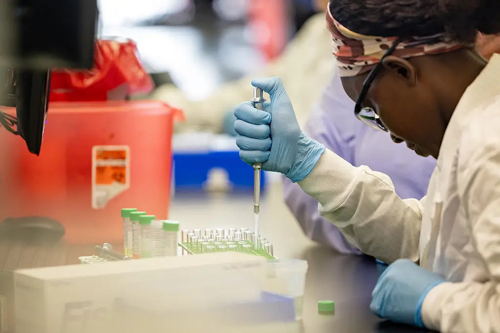Medical Laboratory Technician (MLT) performing manual sample preparation and pipetting procedures in a medical lab setting