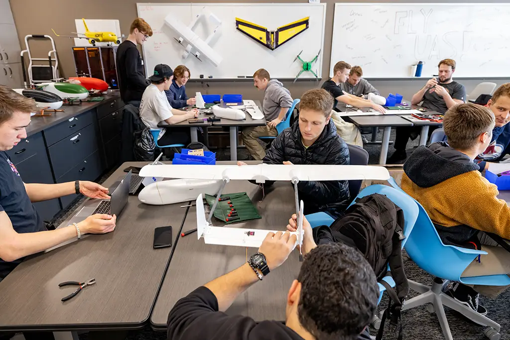 Aerospace engineering students collaborating on the design and assembly of Unmanned Aircraft Systems (UAS) in a dedicated university lab.