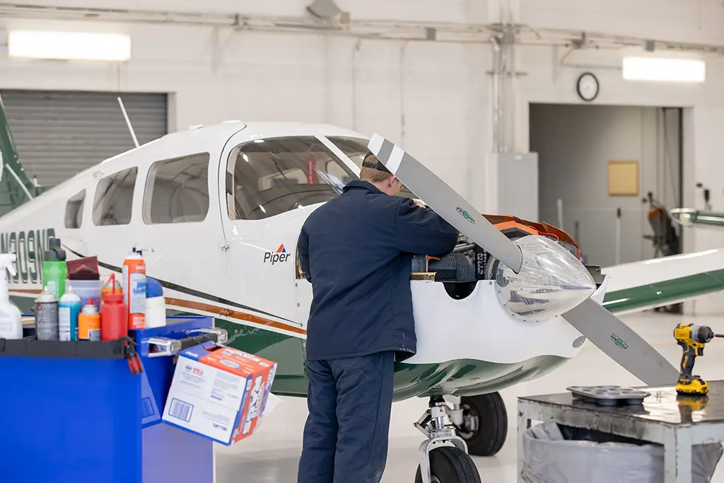 A student applies systems engineering principles while performing maintenance and integration on an aircraft engine in the university hangar.