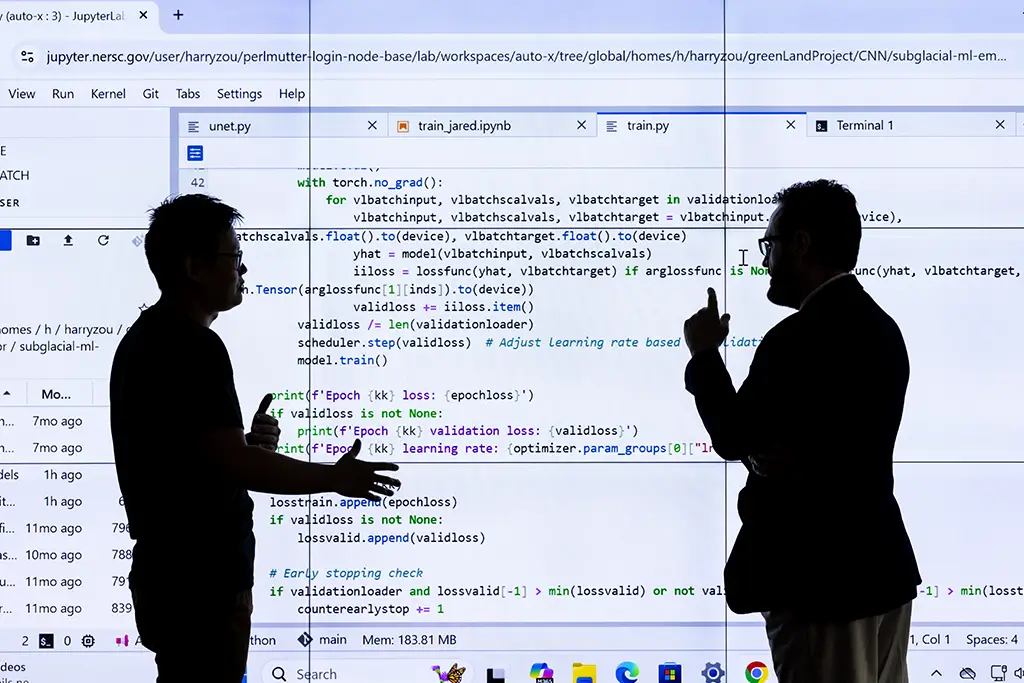 Two people silhouetted against a projected screen of machine learning code, illustrating collaboration and ethical dialogue in responsible AI development