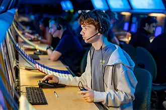  An air traffic control student wearing a headset works at a radar console in a darkened lab.