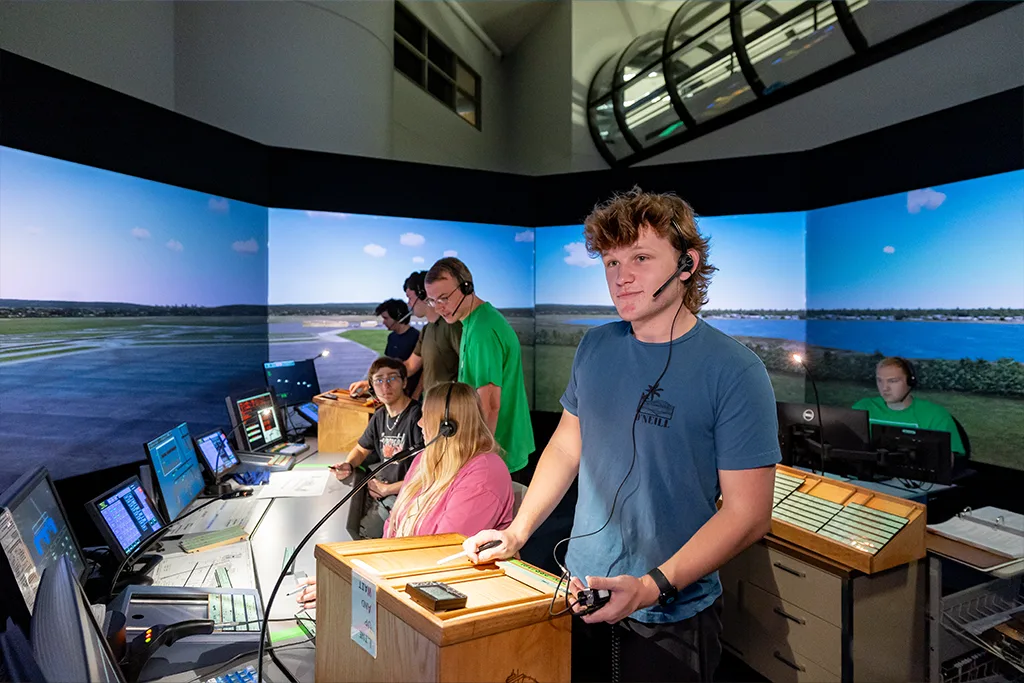 An air traffic control student wearing a headset directs traffic in the 360-degree tower simulator.