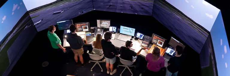 Overhead view of students staffing radar and control stations inside the 360-degree tower simulator.