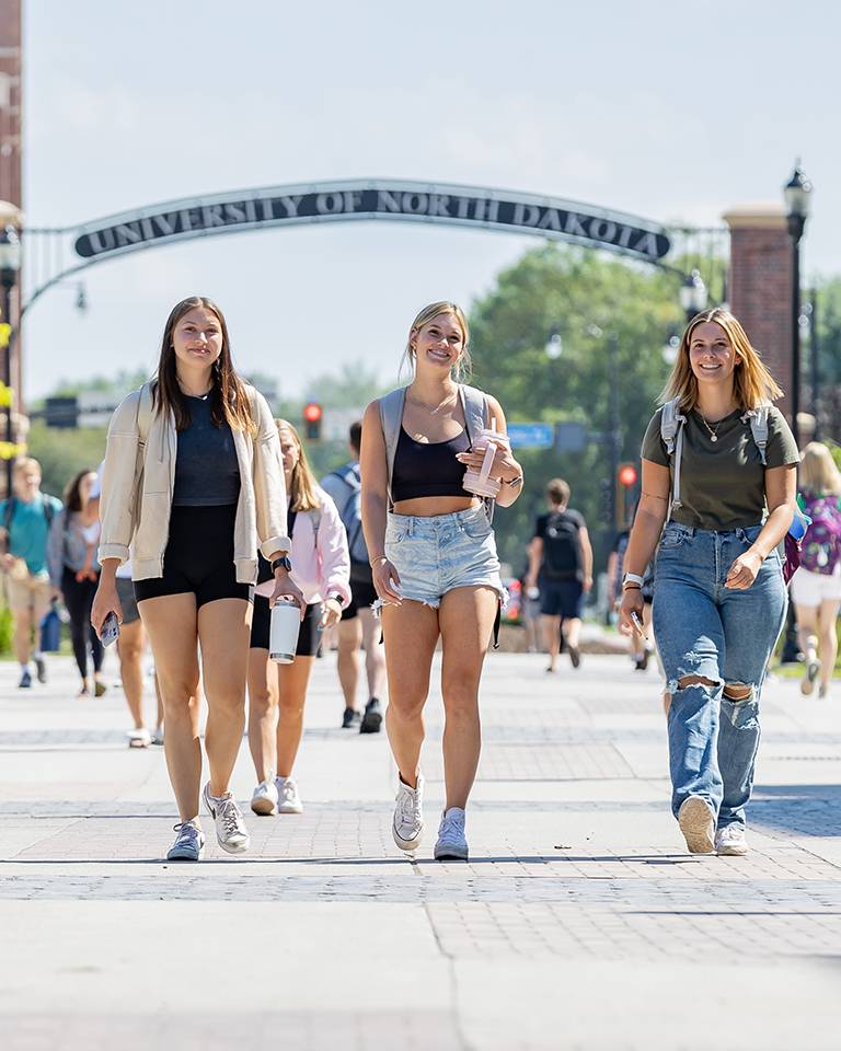 Group of female students walking by UND arch