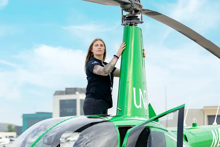 Ali Moses standing on airport runway with helicopter