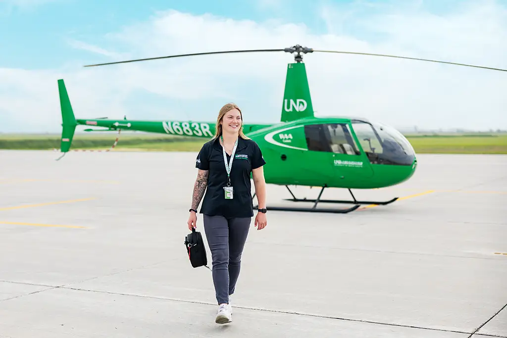 Ali walking on airport runway with helicopter in background