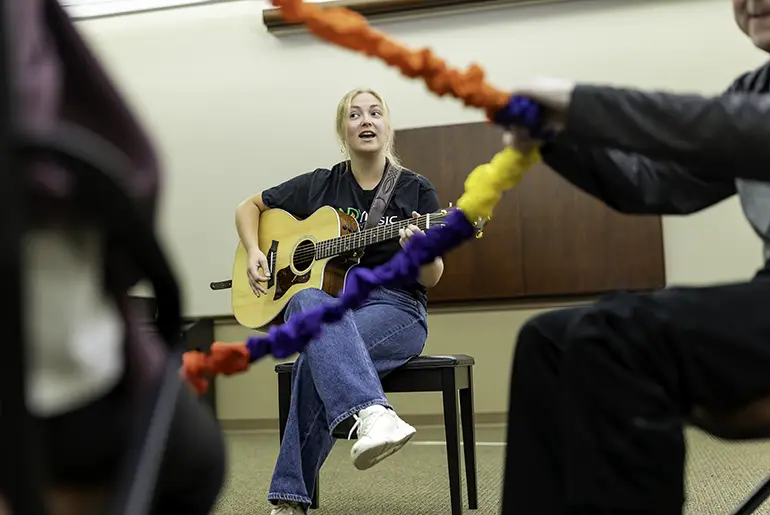 Aubrey playing an instrument in a music therapy class