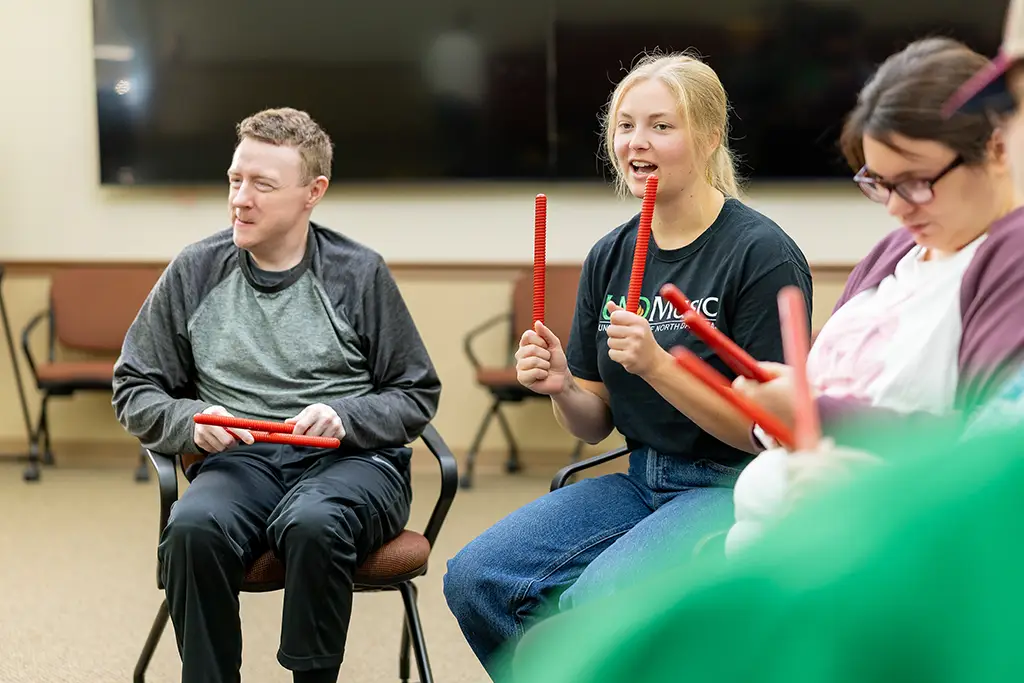Aubrey using drumsticks in music theraphy session