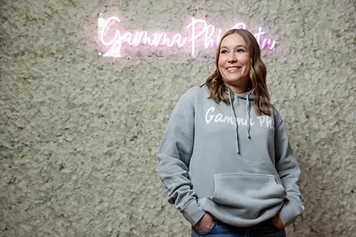 Chloe Aamodt standing in front of pink Greek neon sign