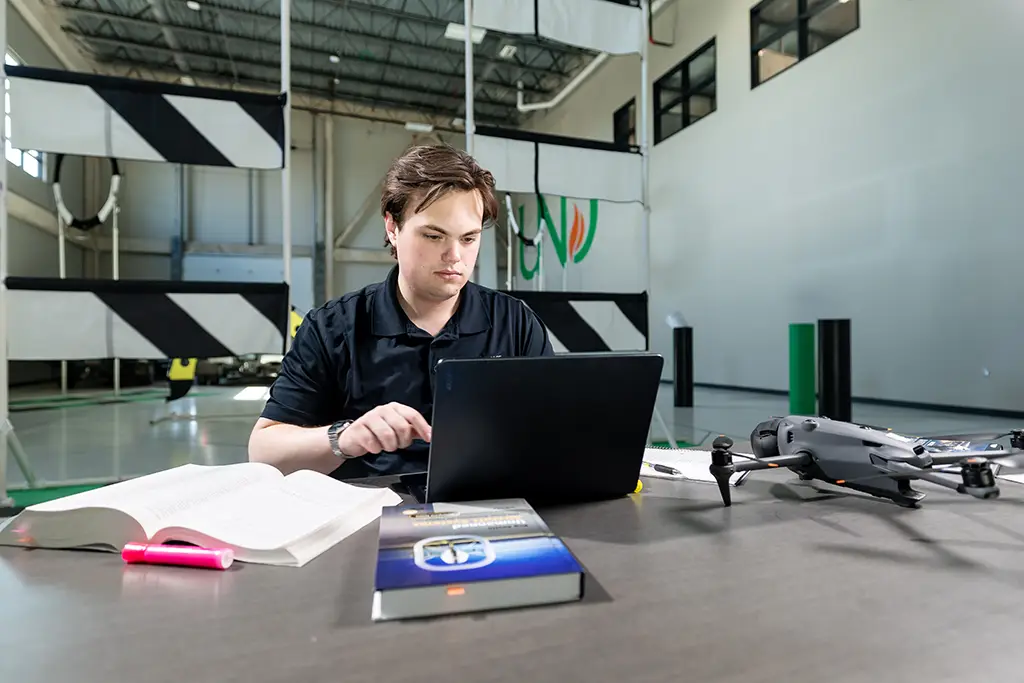 greyson working with laptop on und campus