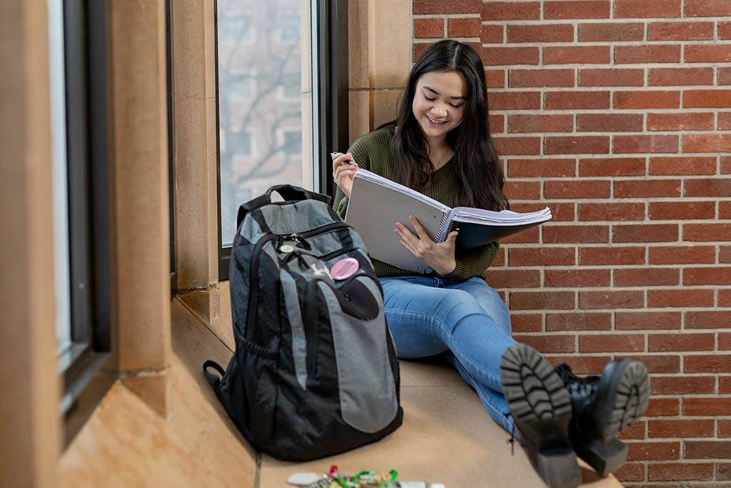 Lauren McCreary studying in window seat