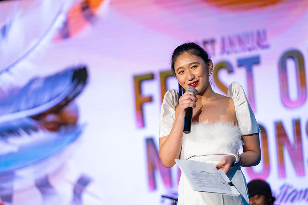 Nichole Dumlao holds a microphone on stage at Feast of Nations.