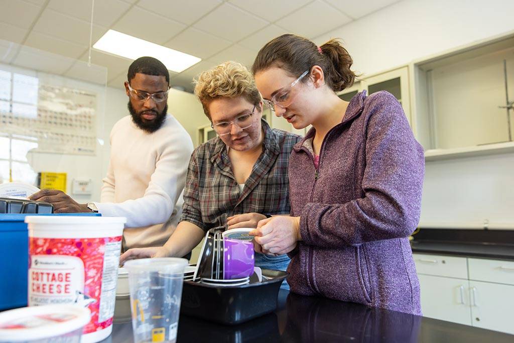 three students looking at plastic