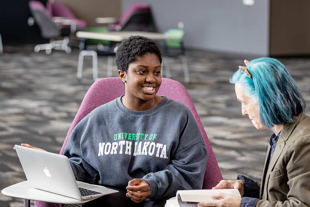 Woman smiling sitting next to professor