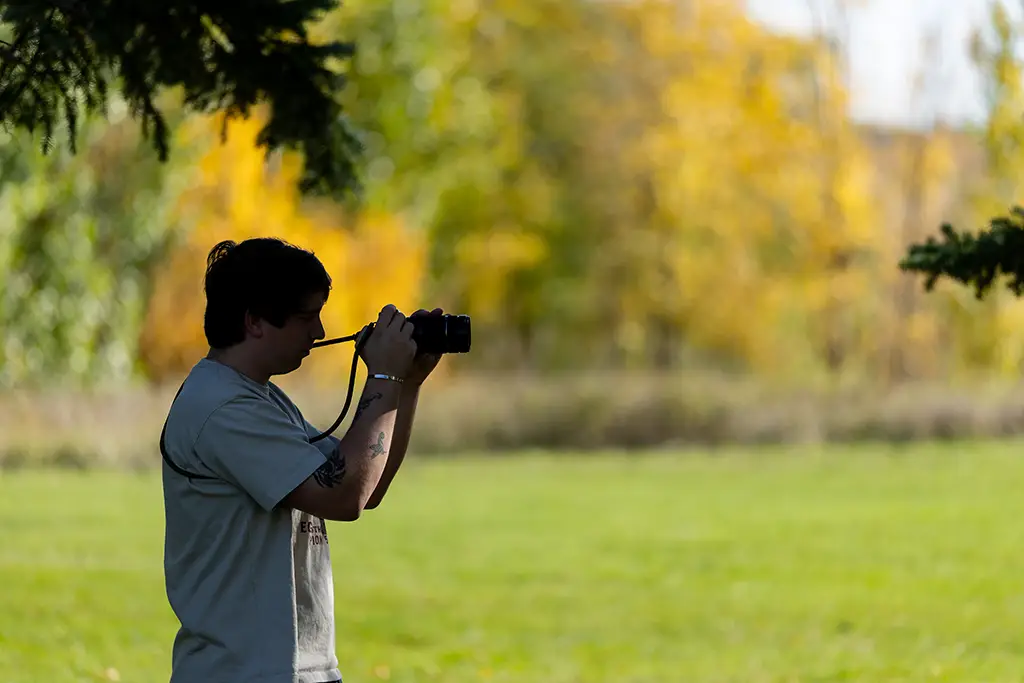 tucker taking a photo surrounded by fall colors and trees