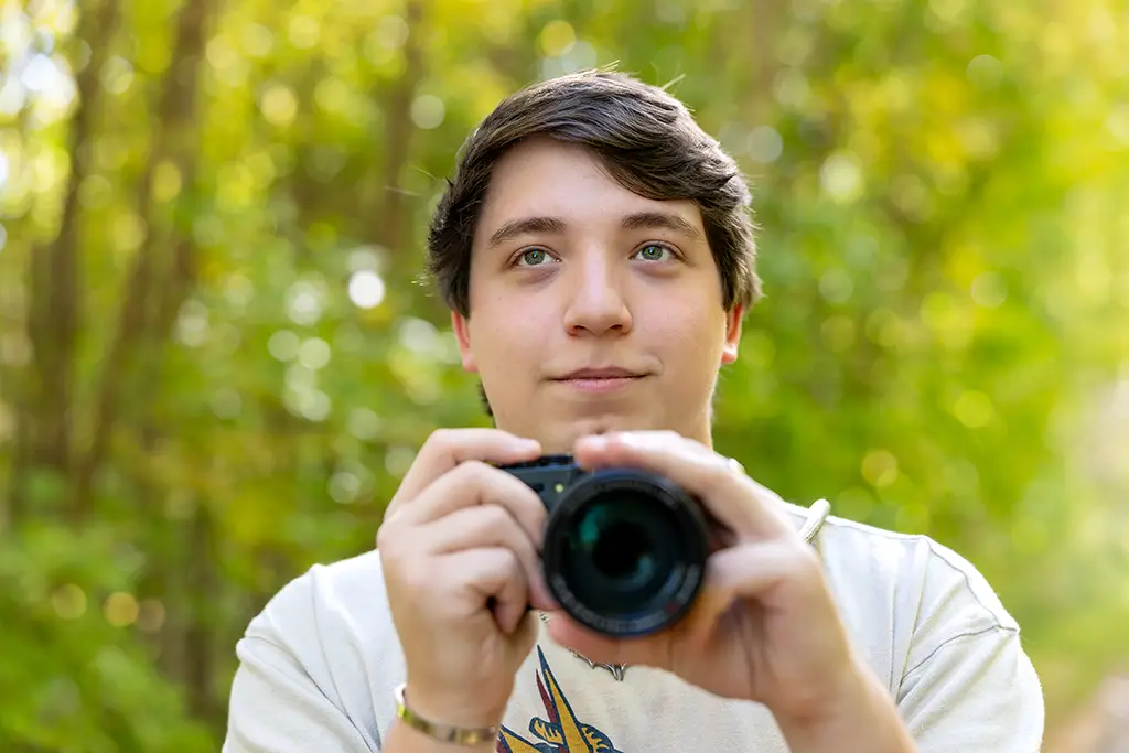 tucker holding a camera and smiling