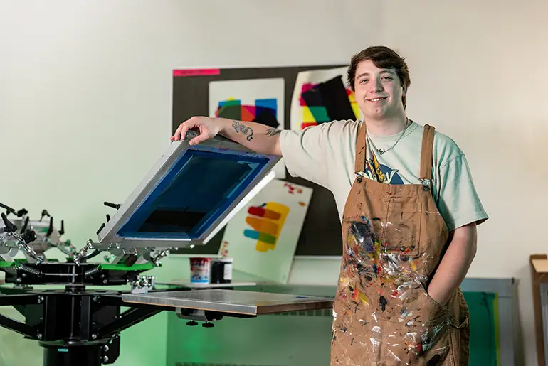 Tucker Schoneberg standing in UND art classroom