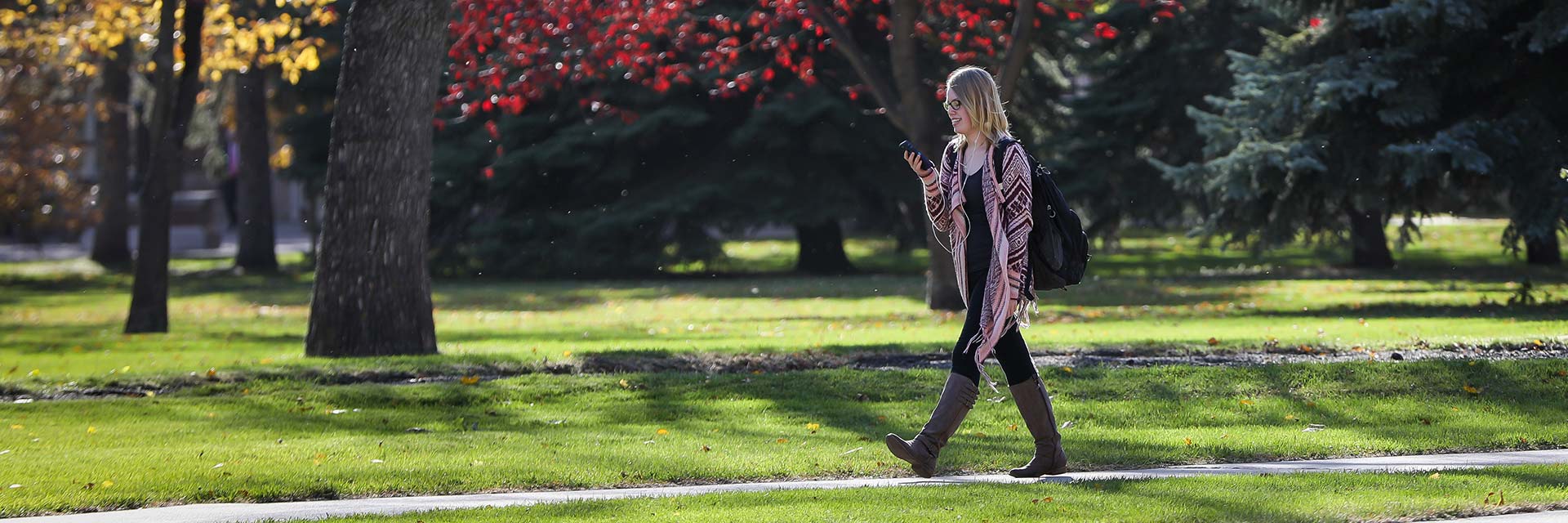 student walking on campus and checking phone